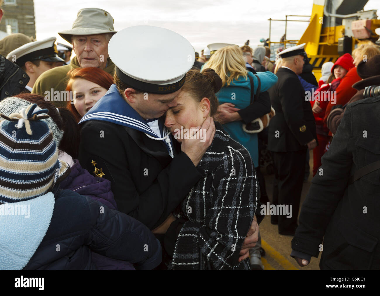 Un marinaio viene accolto dalla sua famiglia mentre i suoi compagni di nave cercano la loro nave dopo che la loro nave, HMS Dragon, è tornato a Portsmouth dopo otto mesi di spiegamento da nubile nel Golfo e nel Mediterraneo. Foto Stock