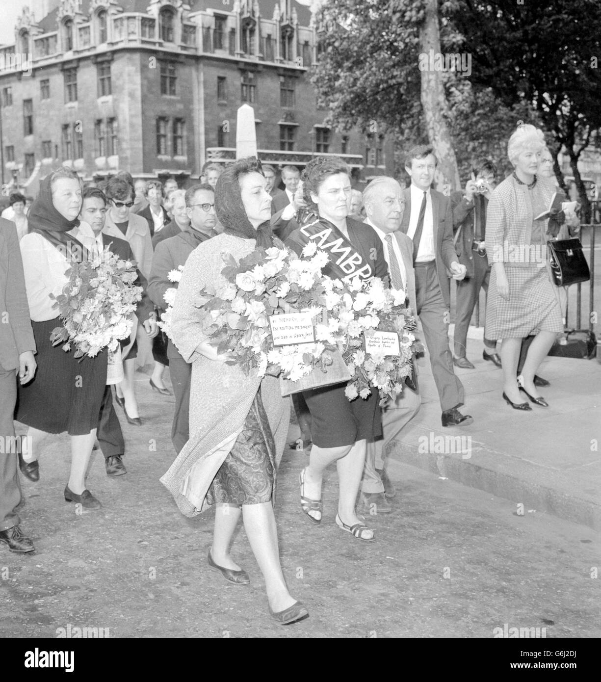 La sig.ra Betty Ambatielos (centro), moglie del capo dei marinai greci incarcerati, porta con sé una corona che riporta la leggenda "in memoria di 500 prigionieri politici greci morti nelle carceri greche", come pure altre donne che portavano anche tributi, Si avvicina alle porte dell'Abbazia di Westminster dopo la visita del re Paolo e della regina Frederika degli Hellenes. La polizia ha allontanato il gruppo. All'arrivo della coppia reale greca alla stazione di Victoria per la visita di Stato, la signora Ambatielos gridò: "Liberalo, liberalo mio marito". È stata portata dalla polizia in un corridoio ed è stata rilasciata dopo il trasporto Foto Stock