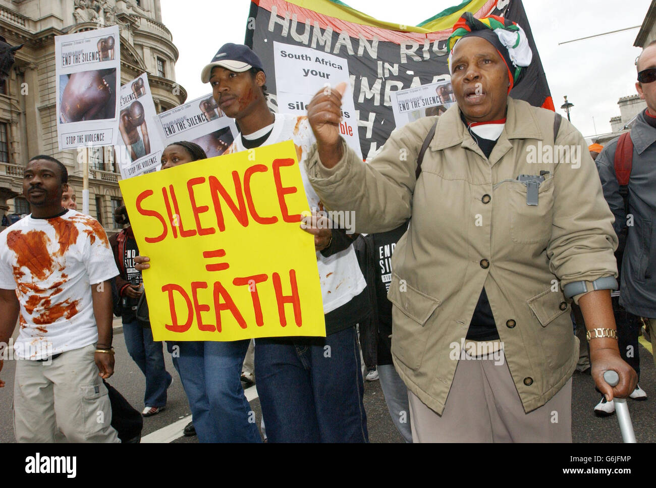 Calitas Motola, 56, (a sinistra) torturato sotto il regime del presidente Mugabe per aver sostenuto un partito di opposizione si unisce alla fine la Silence Coalition, un gruppo di protesta contro le violazioni dei diritti umani in Zimbabwe, mentre salgono a Whitehall, Londra. Foto Stock