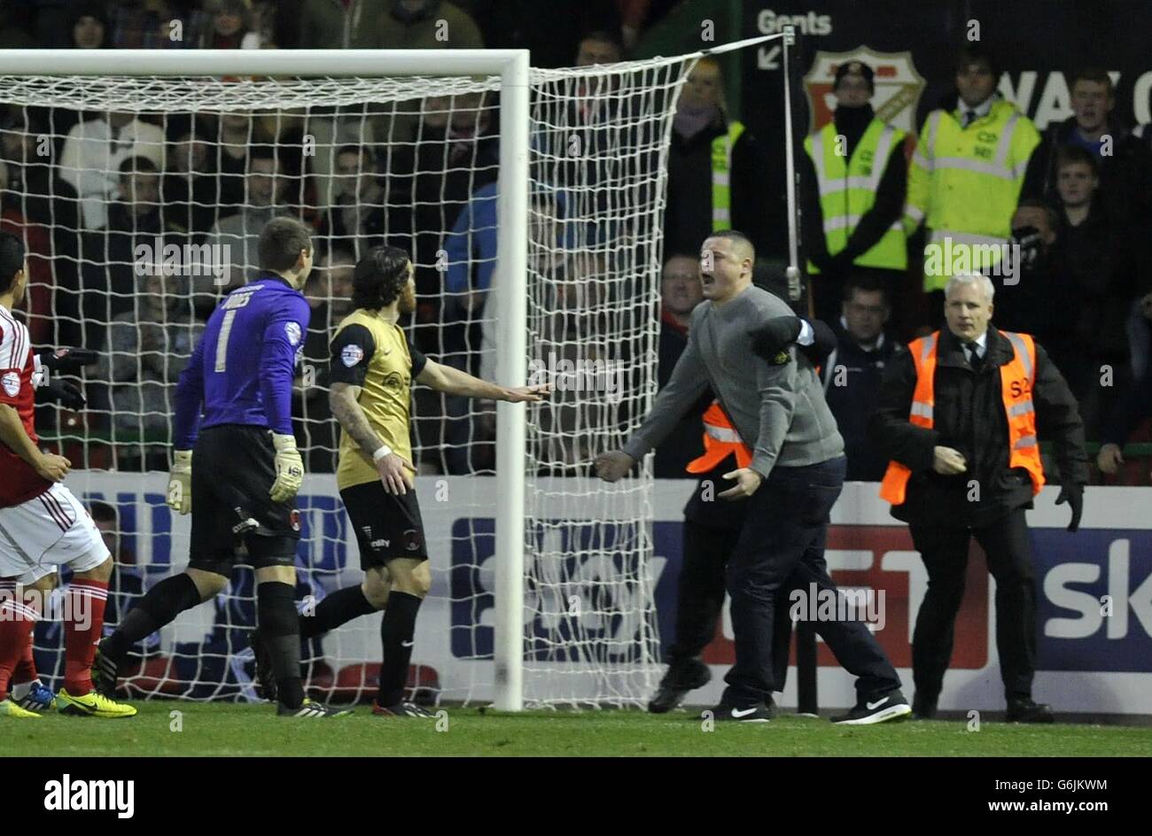 Un fan della città di Swindon corre in campo e affronta il Roman Vincelot di Leyton Orient durante la partita Sky Bet League Two al County Ground, Swindon. Foto Stock