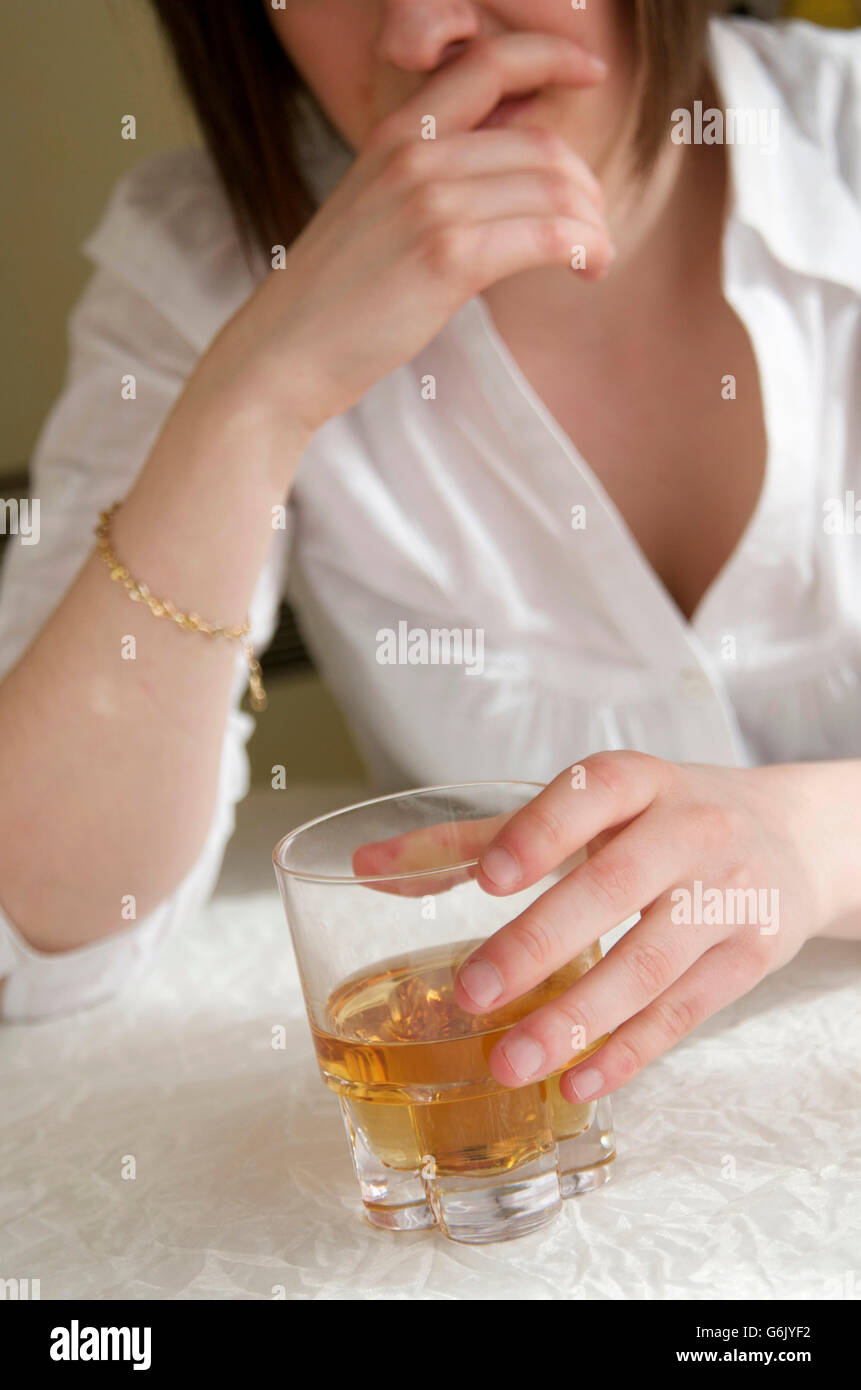 Donna che mantiene un bicchiere di liquore duro, alcolismo femmina Foto Stock