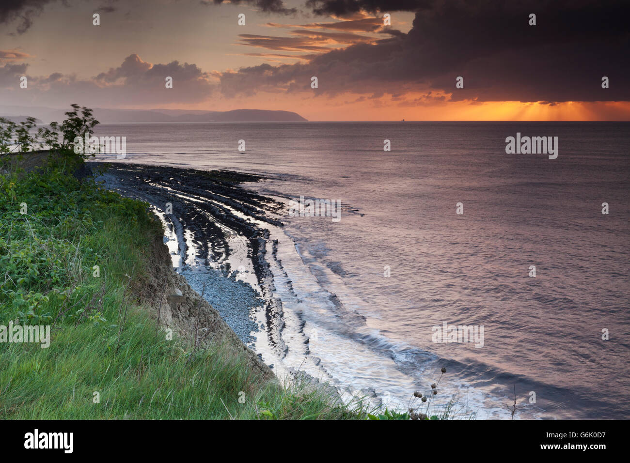 Regolazione del sole che splende attraverso una nube di pesanti con raggi oltre il canale di Bristol, dalle falesie sopra Kilve Beach, Somerset Foto Stock