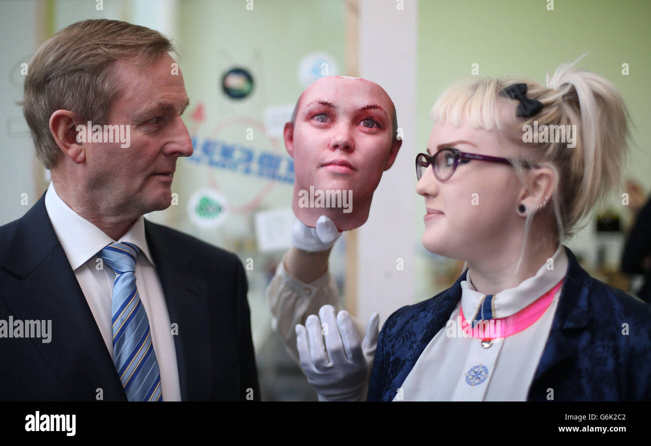 Taoiseach Enda Kenny pone con lo studente Ling Heaney e una maschera come egli aiuta a lanciare il programma di quattro nuove mostre per il 2014 presso la Science Gallery al Trinity College. La maschera è stata creata usando tracce di DNA umano trovato su mozziconi di sigaretta che litterano le strade di Dublino che sono stati portati in un laboratorio ed è stata eseguita un'estrazione di DNA. Certe regioni del DNA sono state amplificate usando una tecnica chiamata reazione a catena PCR-polimerasi. Ciò rende possibile studiare certe regioni del genoma che tendono a variare da persona a persona, note come polimorfismi di nucleotide singolo (SNP). Foto Stock
