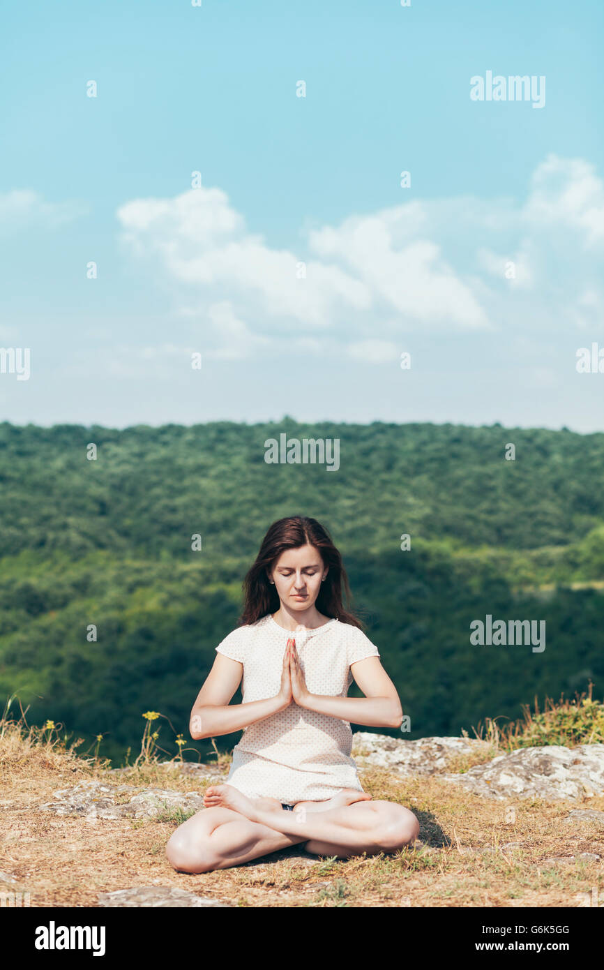 Giovane donna meditando sulla scogliera Foto Stock