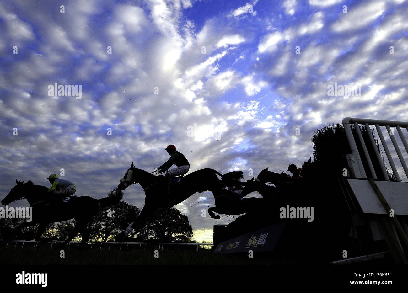 Tramonto invernale sul Wetherby Race Course mentre i corridori del William Hill Yorkshire Winter Festival saltano una delle recinzioni durante la giornata di campagna all'ippodromo di Wetherby, Wetherby. Foto Stock