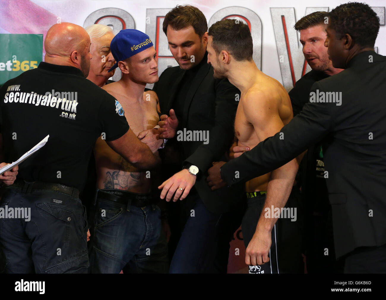 Il promotore Eddie Hearn e diverse guardie di sicurezza si mettono a separare George Grove (a sinistra) e Carl Froch al Weigh in al Manchester Central, Manchester. Foto Stock