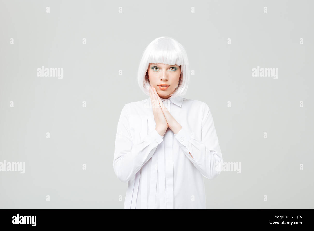 Ritratto di bella sorridente giovane donna in parrucca bionda e camicia su sfondo bianco Foto Stock