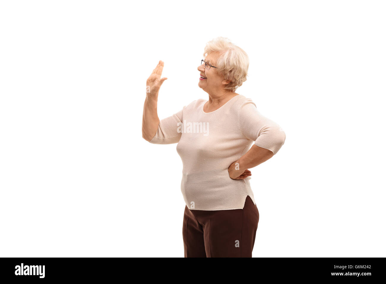 Donna anziana sventolare a qualcuno con la sua mano isolati su sfondo bianco Foto Stock