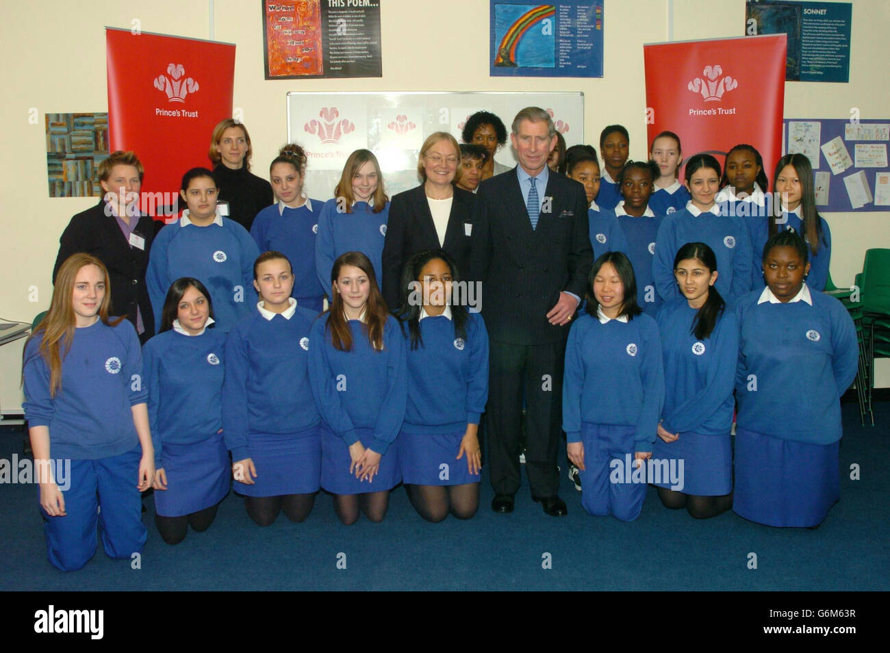 Il Principe del Galles (centro) ha la sua fotografia scattata con i bambini e il personale durante una visita alla Haggerston Girls School a Hackney, Londra orientale. Carlo lasciò la scuola in una delle zone più povere della città, per gridare 900 alunni, che si radunarono nel parco giochi per avere la possibilità di scuotere la mano. Foto Stock