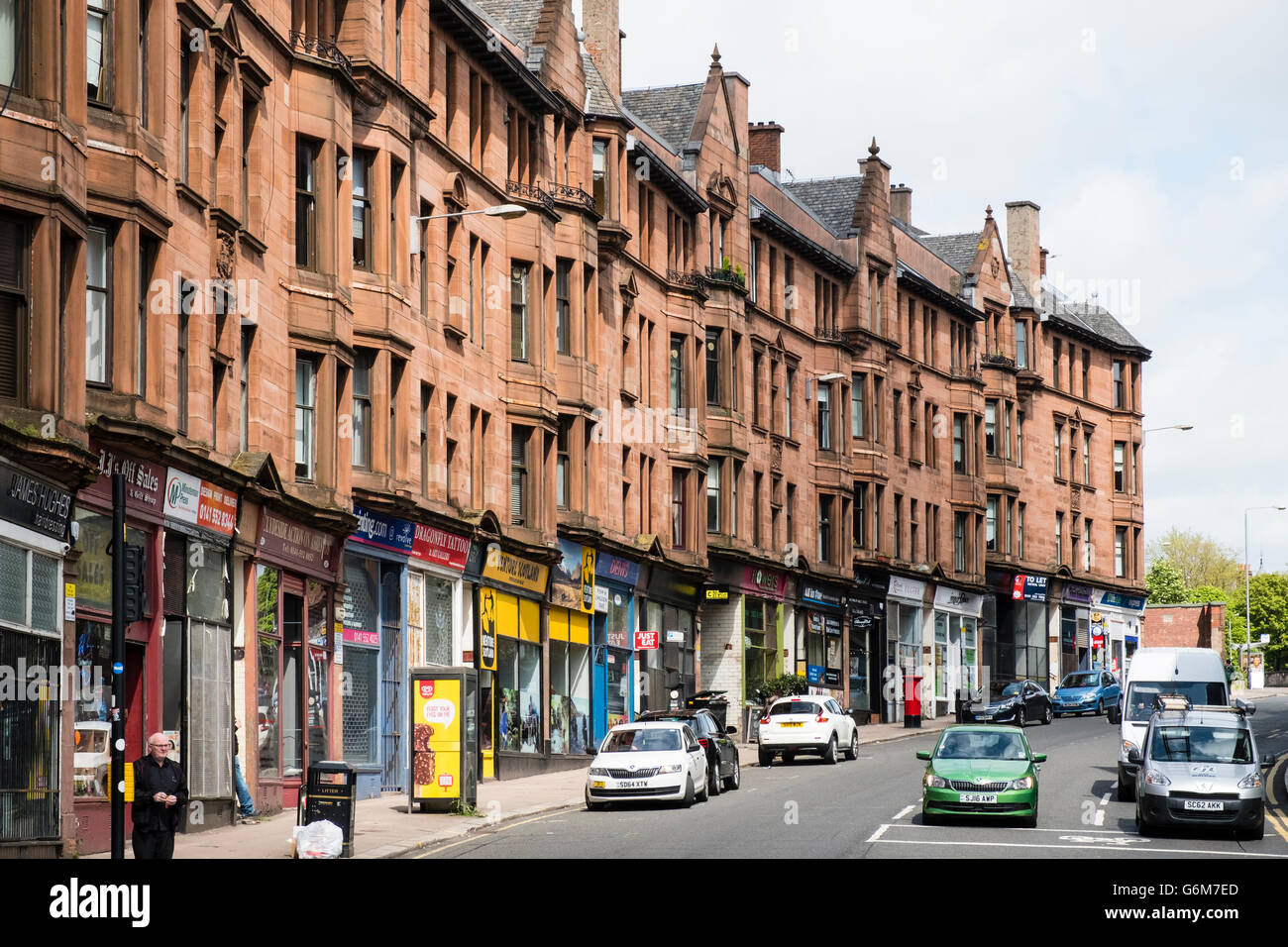 Vista lungo High Street con pietra arenaria tradizionale tenement edifici di appartamenti in East End di Glasgow, Scotland, Regno Unito Foto Stock