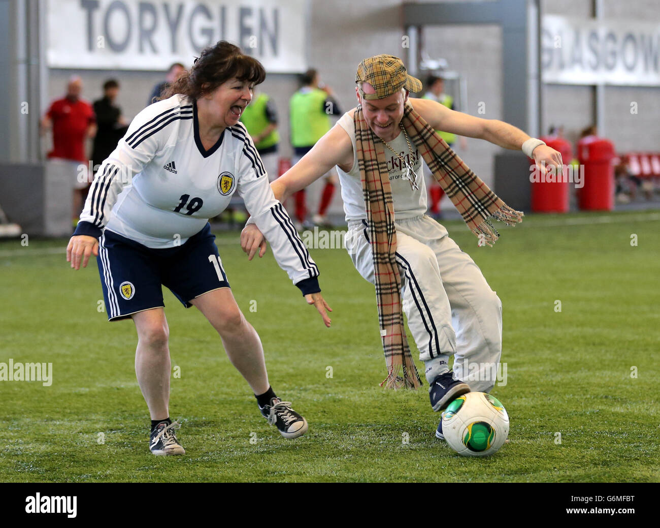 I comici Janey Godley sfidano il Wee Man durante una partita di calcio benefica al Toryglen Football Center di Glasgow per raccogliere fondi per le vittime del Clusha Helicopter crash. Foto Stock