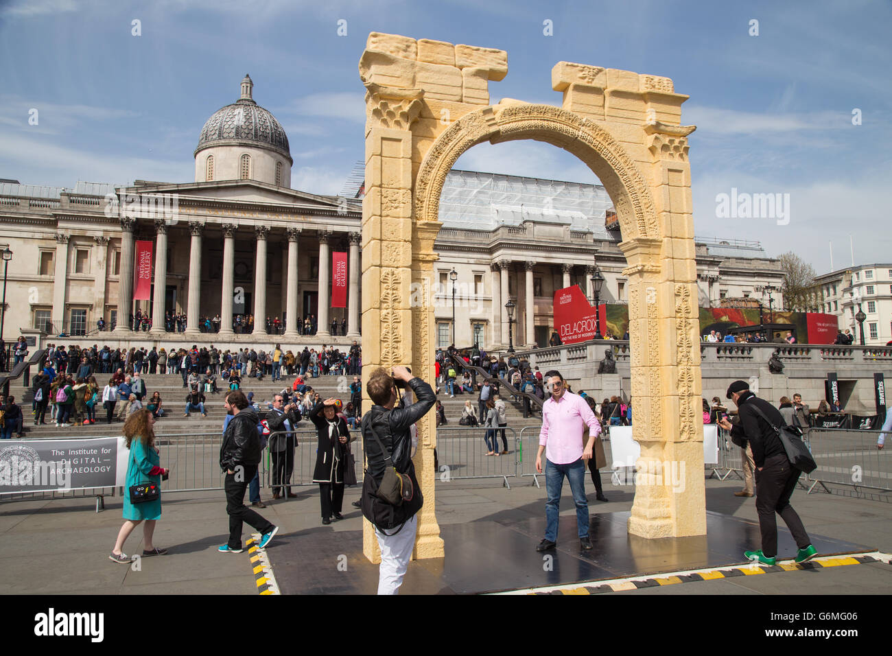 Visitatore pone per la foto sotto la replica di Palmyra di arco di trionfo in Trafalgar Square, Londra, Regno Unito. Aprile 2016. Foto Stock