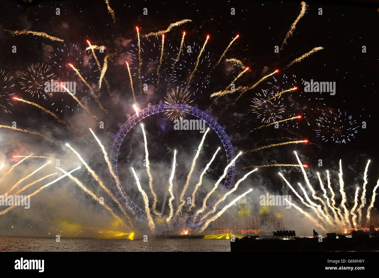 Fuochi d'artificio illuminano il cielo sopra il London Eye a Londra centrale durante i festeggiamenti di Capodanno. Foto Stock