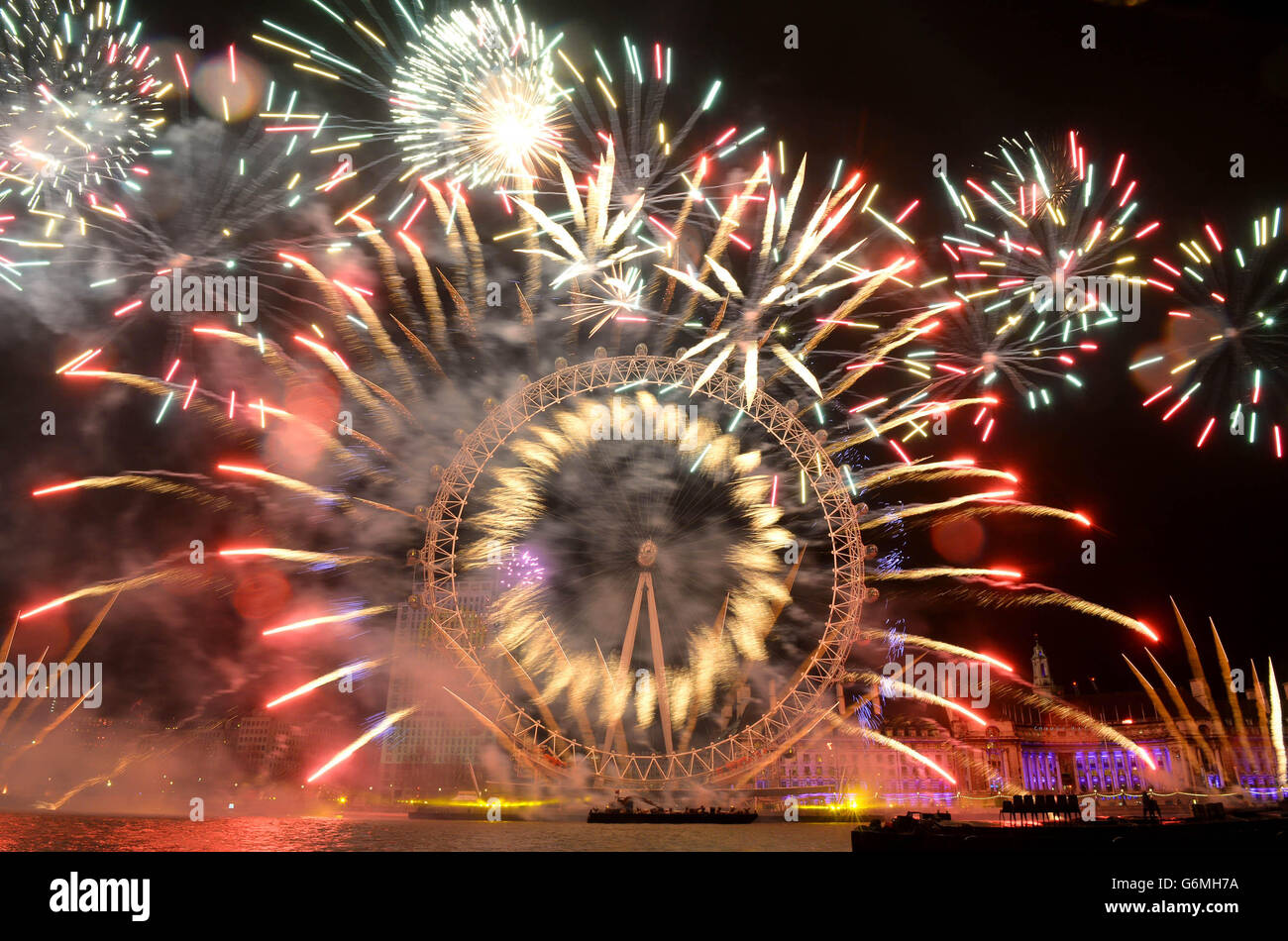 Fuochi d'artificio illuminano il cielo sopra il London Eye a Londra centrale durante i festeggiamenti di Capodanno. Foto Stock
