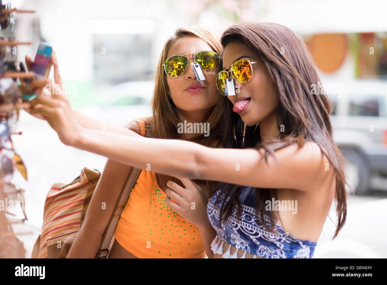 Due giovani donne cercando gli occhiali da sole sul e prendendo un selfie Foto Stock