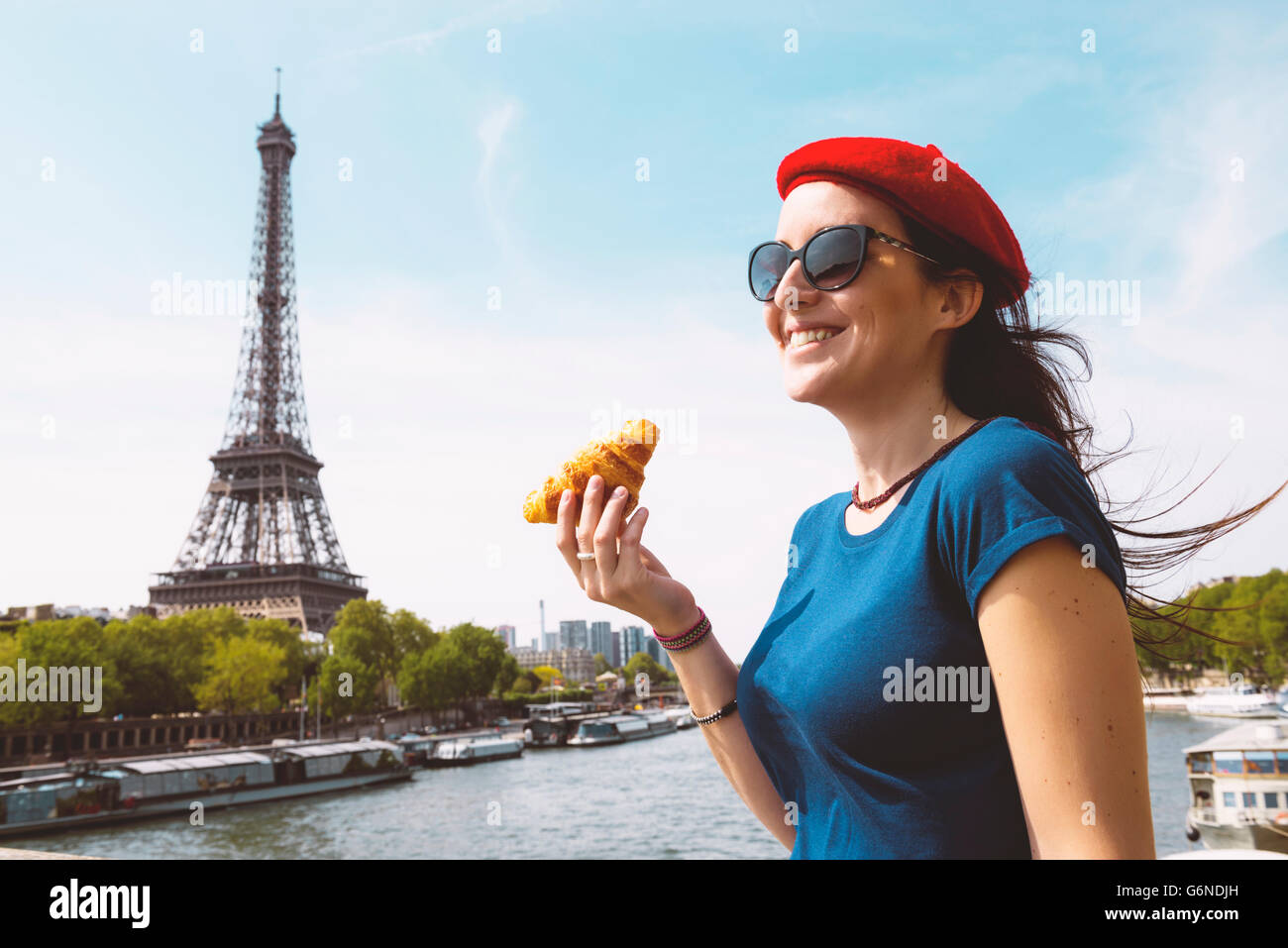 Francia, Parigi, donna con croissant in piedi nella parte anteriore del Fiume Senna e dalla Torre Eiffel Foto Stock