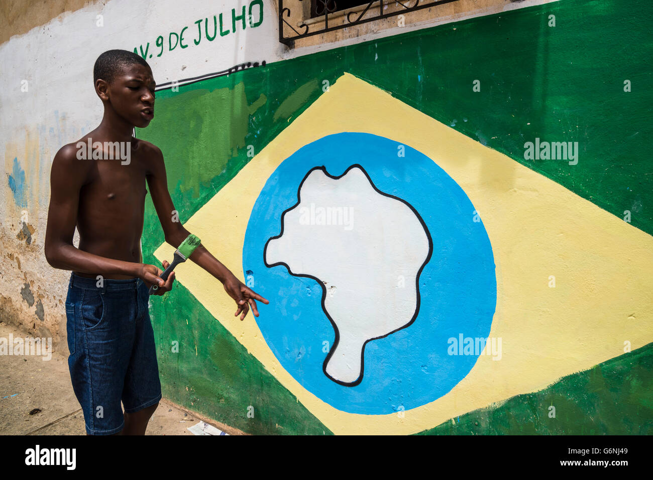 Ragazzo adolescente pittura bandiera brasiliana, Gentois comunità, Bairro da Federação, Salvador, Bahia, Brasile Foto Stock