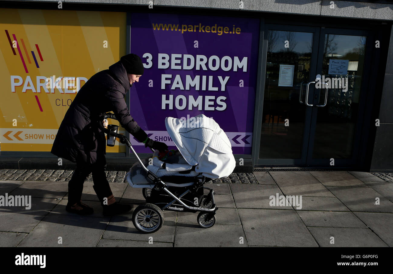 Vita Lisauskaite ruota sua figlia bambino passato una vetrina pubblicità case di famiglia a Clongriffin, Dublino. Foto Stock