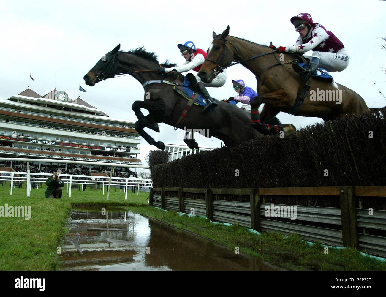 Padre Abraham riden di Joe Tizzard guida Zen riden di Brian Crowley (sul lato sinistro) ed eventuale vincitore del Double Honor riden di Richard Johnson (farside) sul salto in acqua al primo giro della lettura serale Post Novices' Steeple Chase a Newbury. Foto Stock