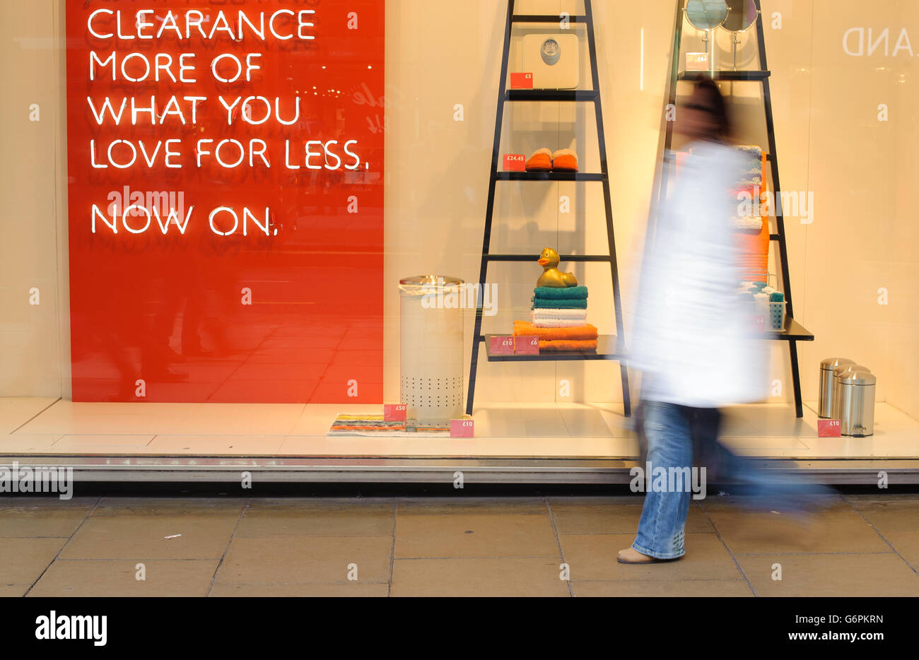 Shopping stock. Uno shopper passa un cartello di vendita in una vetrina di Oxford Street, nel centro di Londra. Foto Stock