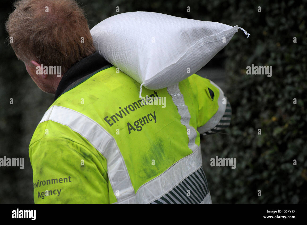 Un operaio dell'Agenzia dell'ambiente trasporta un sacchetto di sabbia al fiume Parrett in Burrowbridge, Somerset, poichè l'inondazione persiste sui livelli. Foto Stock