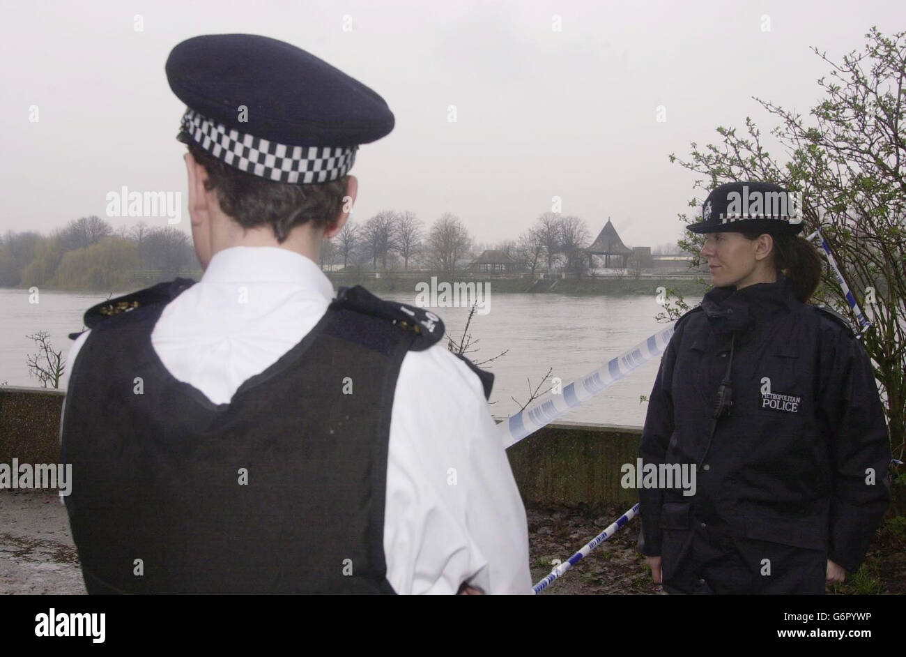 Gli ufficiali della polizia metropolitana si levano in piedi in guardia in un'area cordonata-fuori dal fiume Tamigi in Barnes, Londra sud-ovest dove un corpo è stato scoperto scaricato in una valigia da un passer-by. Gli esperti forensi stavano effettuando una ricerca con le dita sulla scena. Un post mortem doveva essere effettuato sui resti presso la Corte di Kingston Coroner. Foto Stock