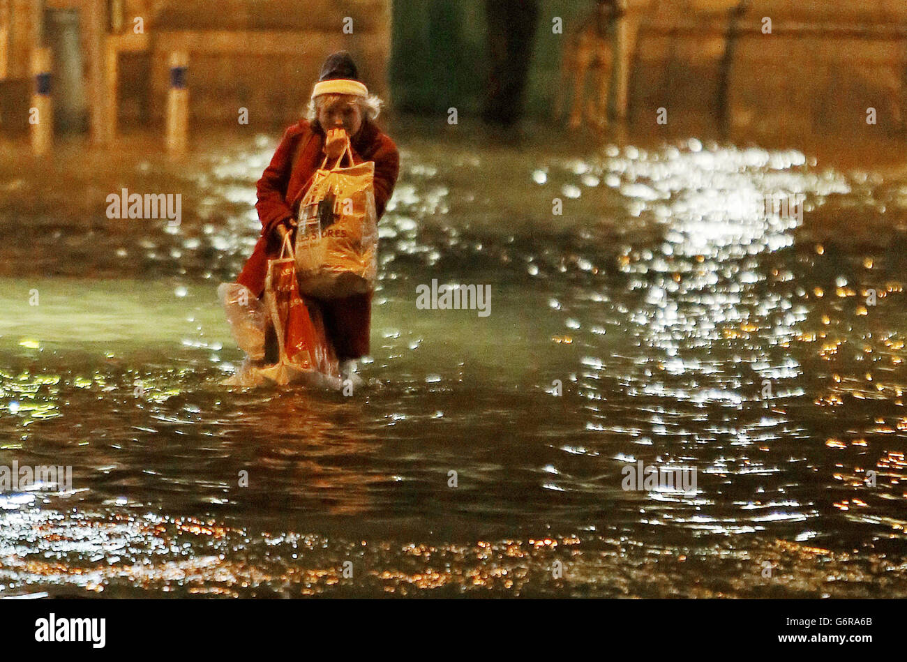 Una donna cammina attraverso l'acqua di alluvione nella città di Cork. Foto Stock