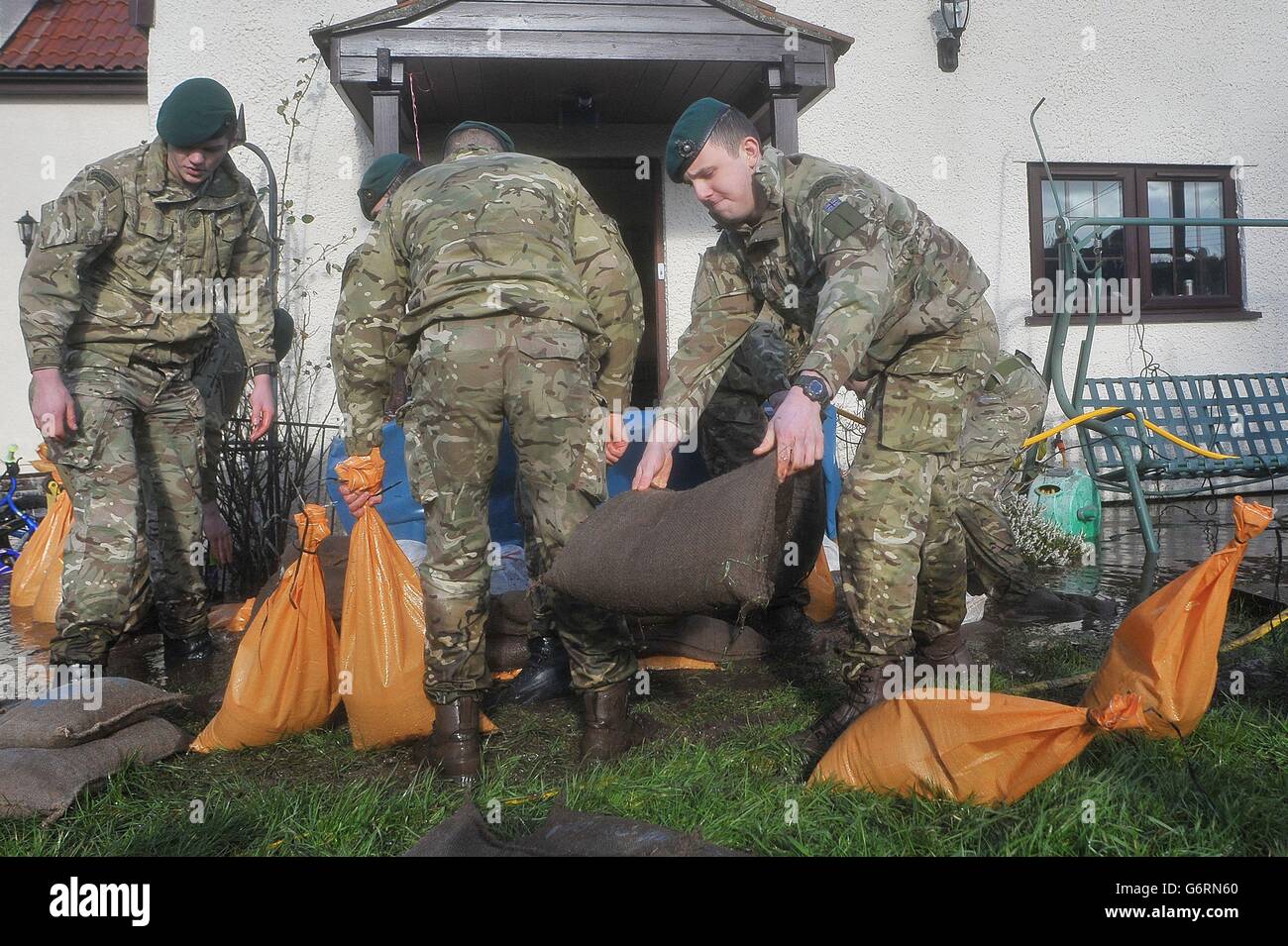 Royal Marines dal 40 Commando aiutare a mettere sacchi di sabbia per proteggere una proprietà in Moorland, Somerset come il villaggio è stato inondato durante la notte. Foto Stock