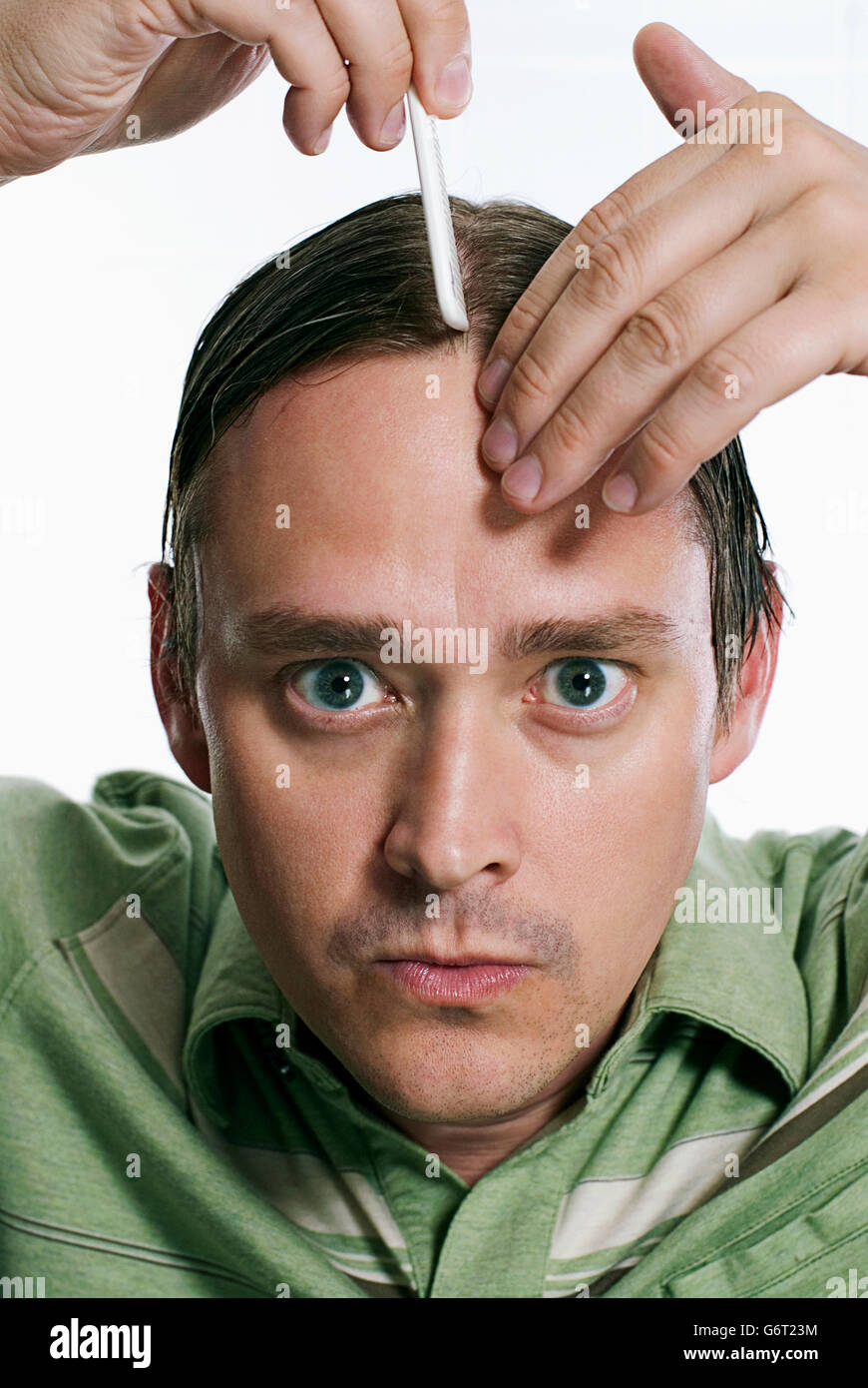 Un uomo il troncaggio i suoi capelli. Foto Stock