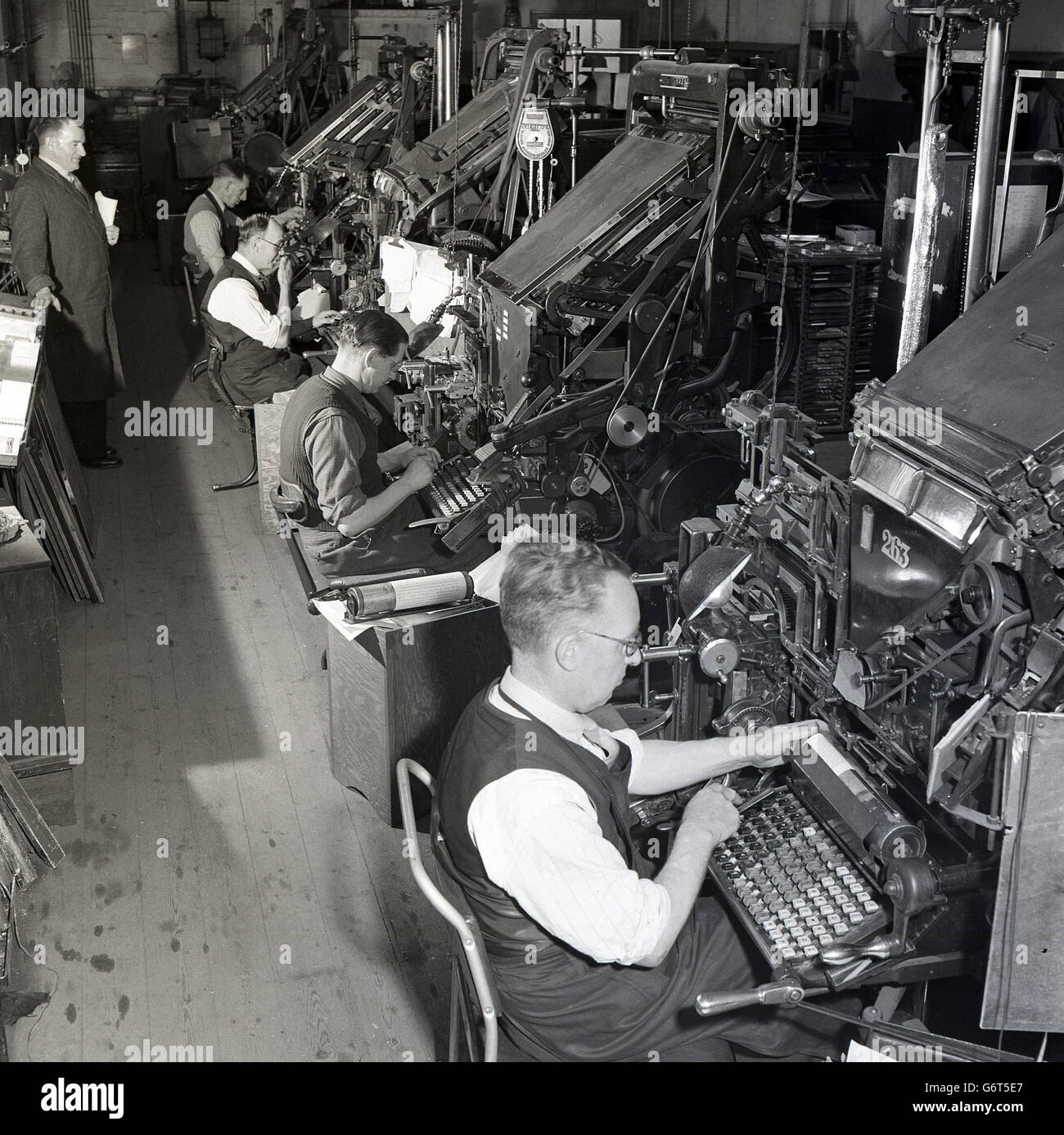 Degli anni Cinquanta, storico, tipista a loro grandi macchine meccaniche sul piano della fabbrica presso l'azienda di stampa Hazell, Watson Veney ( HWV), Hertfordshire, Inghilterra. Foto Stock