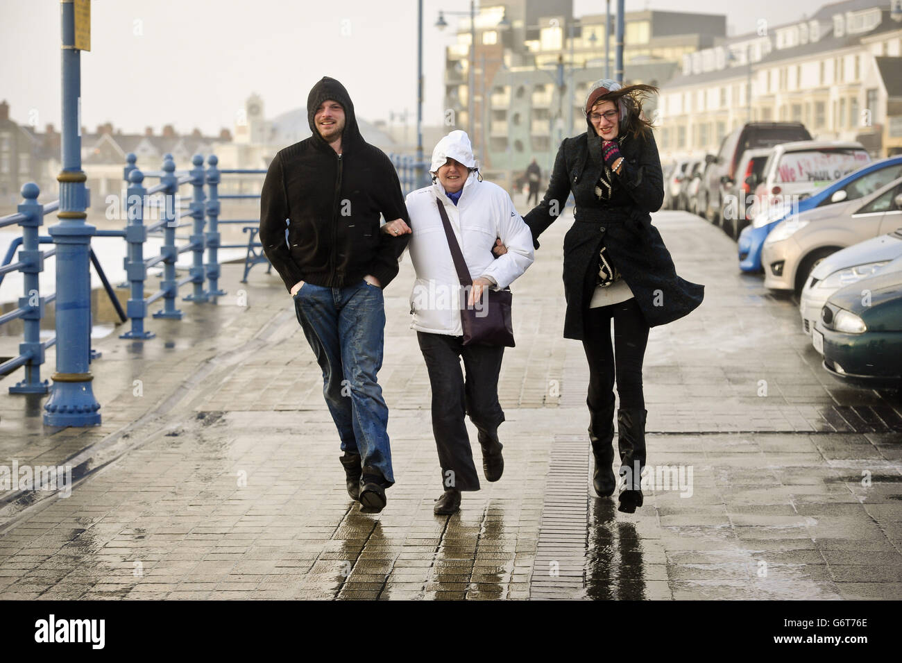 La gente lotta per fare il loro senso lungo l'Esplanade, Porthcawl, Galles del sud, mentre la regione continua ad essere martoriata i venti alti e la pioggia pesante. Foto Stock