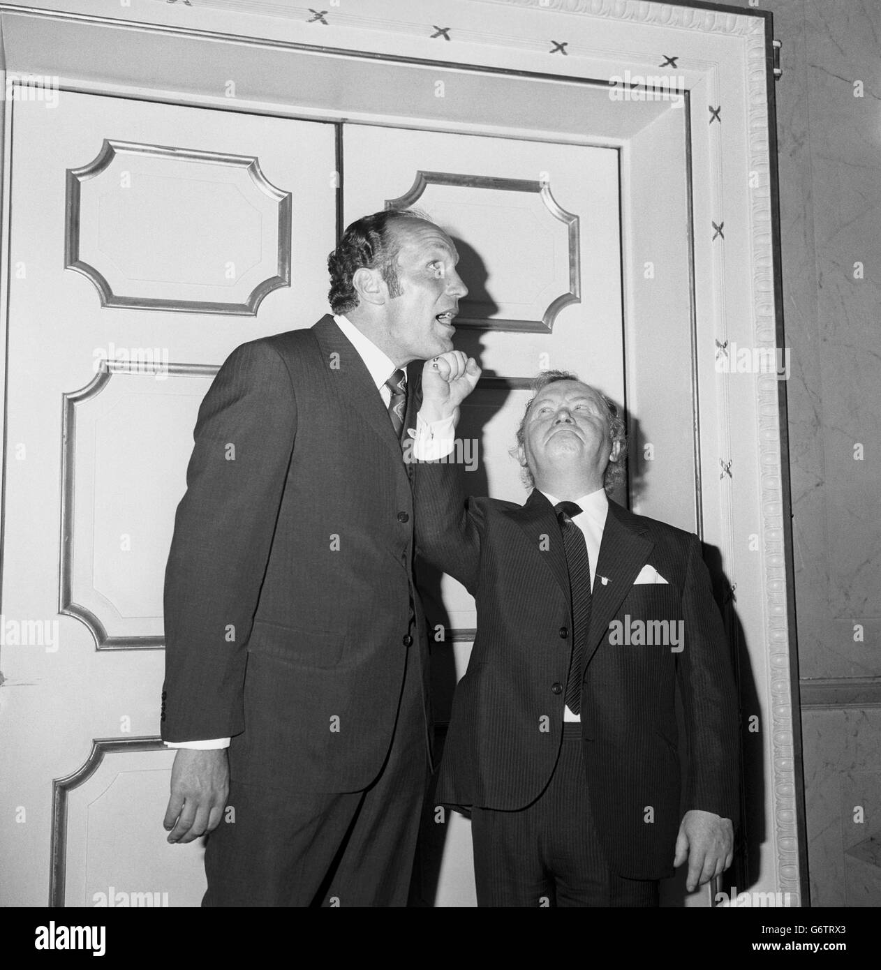 Henry Cooper, ex campione britannico di pesi massimi, lo prende sul mento dal comico tascabile Charlie drake al Dorchester Hotel, Park Lane, dove sono stati tra gli ospiti d'onore al pranzo annuale delle Signore del Variety Club di Gran Bretagna. Foto Stock