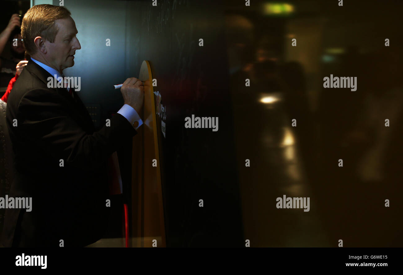 Taoiseach Enda Kenny scrive su un muro durante il lancio del piano d'azione per l'occupazione del 2014, a Wayra Ireland, Sir John Rogerson's Quay, Dublino. Foto Stock