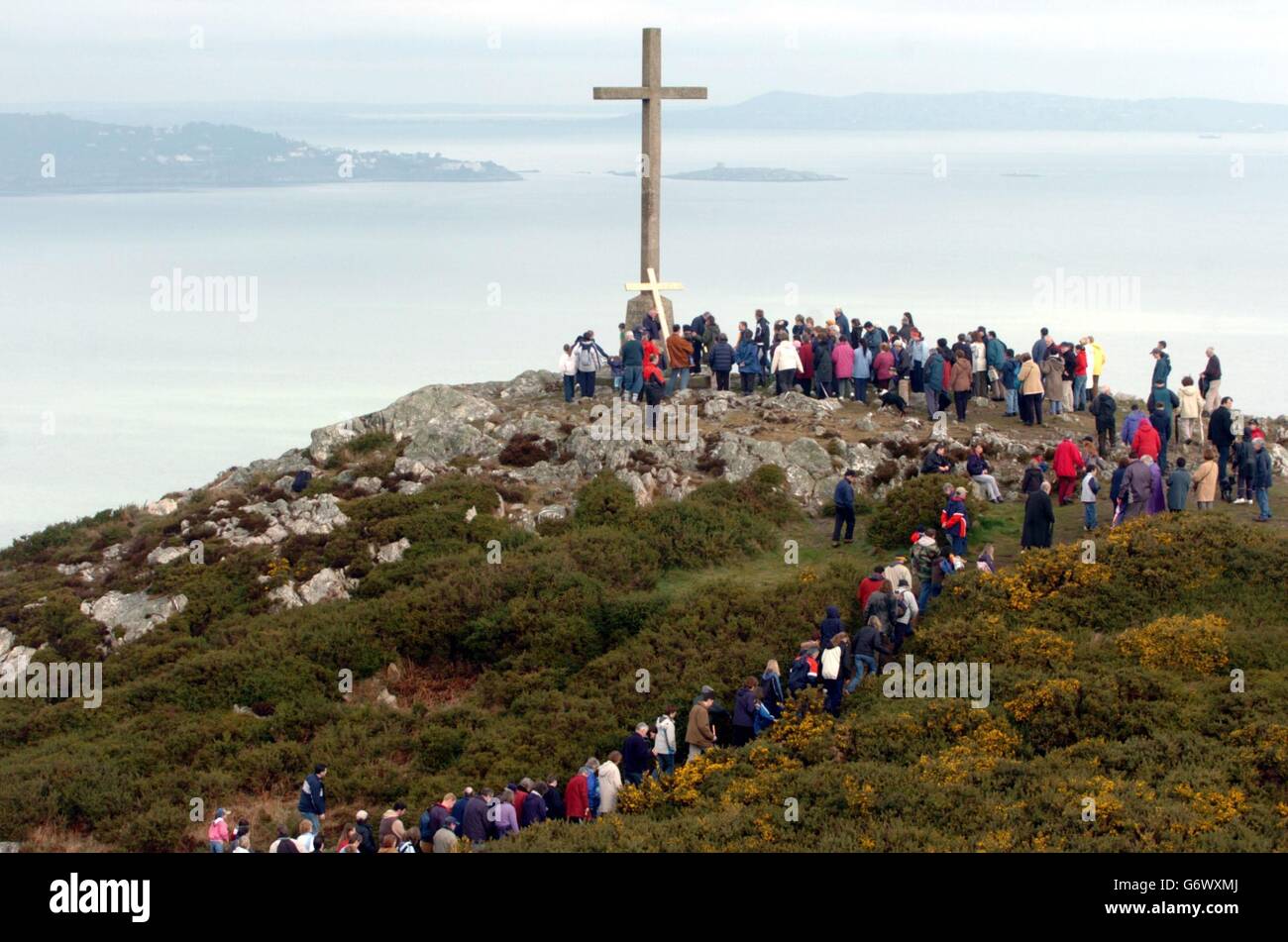 I pellegrini della Chiesa di nostra Signora Regina della Pace, arrivano in cima al Bray Head Point, Co Wicklow, dopo aver preso a turno per portare una croce (piccola croce gialla sotto la grande) sulla montagna, rievocando la Passione di Cristo per il Venerdì Santo. Foto Stock