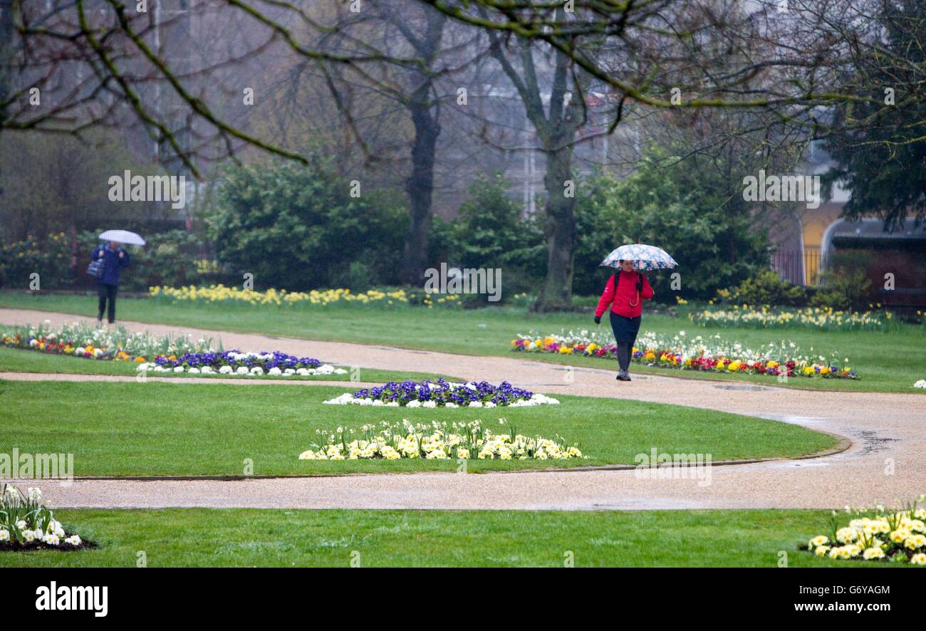 La gente cammina sotto la pioggia ai giardini di Forbury a Reading, Berkshire. Foto Stock