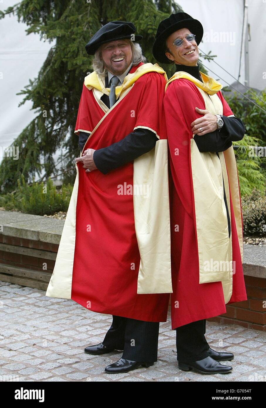Il Bee Gees, Barry (a sinistra) e Robin Gibb posano per i fotografi dopo aver ricevuto la laurea honorary (Dottore of Music) all'Università di Manchester. I fratelli accettarono anche una laurea post-honoris a nome del loro fratello Maurice, morto nel gennaio 2003. Foto Stock