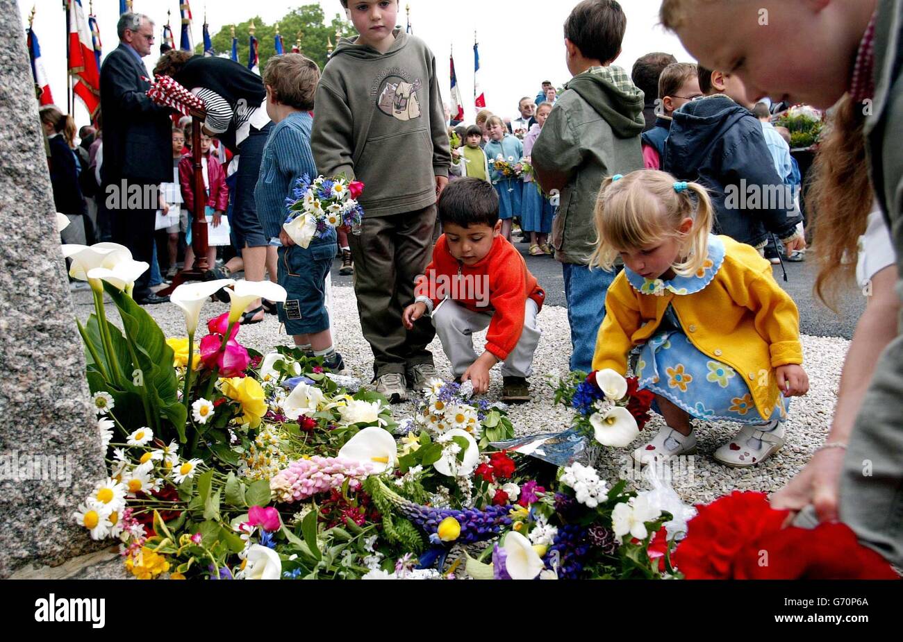 Gli studenti francesi di Magneville in Normandia posano fiori in un memoriale nel loro villaggio ai soldati della 101esima Divisione aerea americana che sono stati abbattuti il D-Day. Questo fine settimana si svolgono eventi in occasione del 60° anniversario dell'invasione alleata dell'Europa. Foto Stock