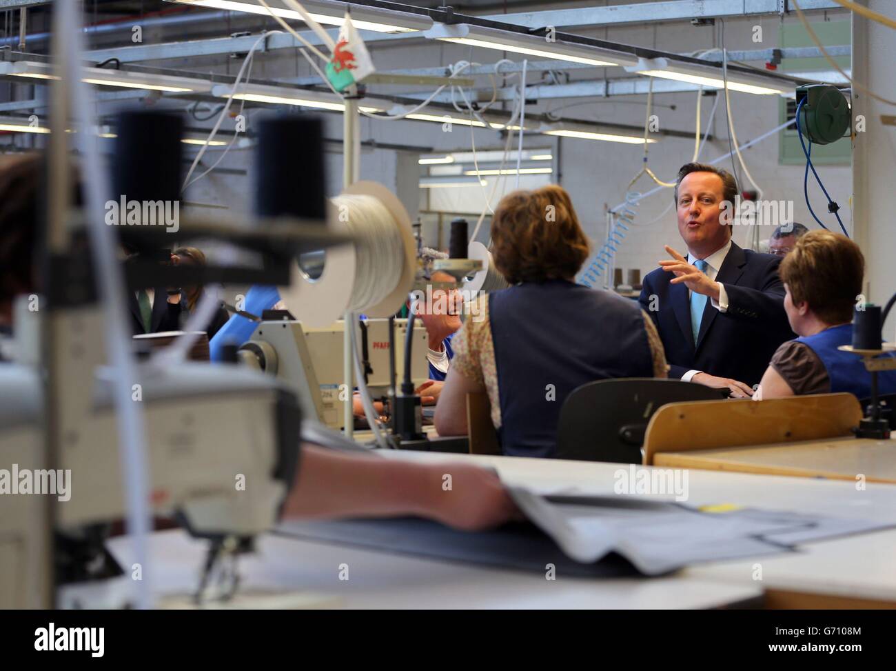 Il primo ministro David Cameron parla con i macchinisti durante una visita alla Westbridge Furniture Ltd, un produttore di divani a Greenfield, Galles del Nord. Foto Stock