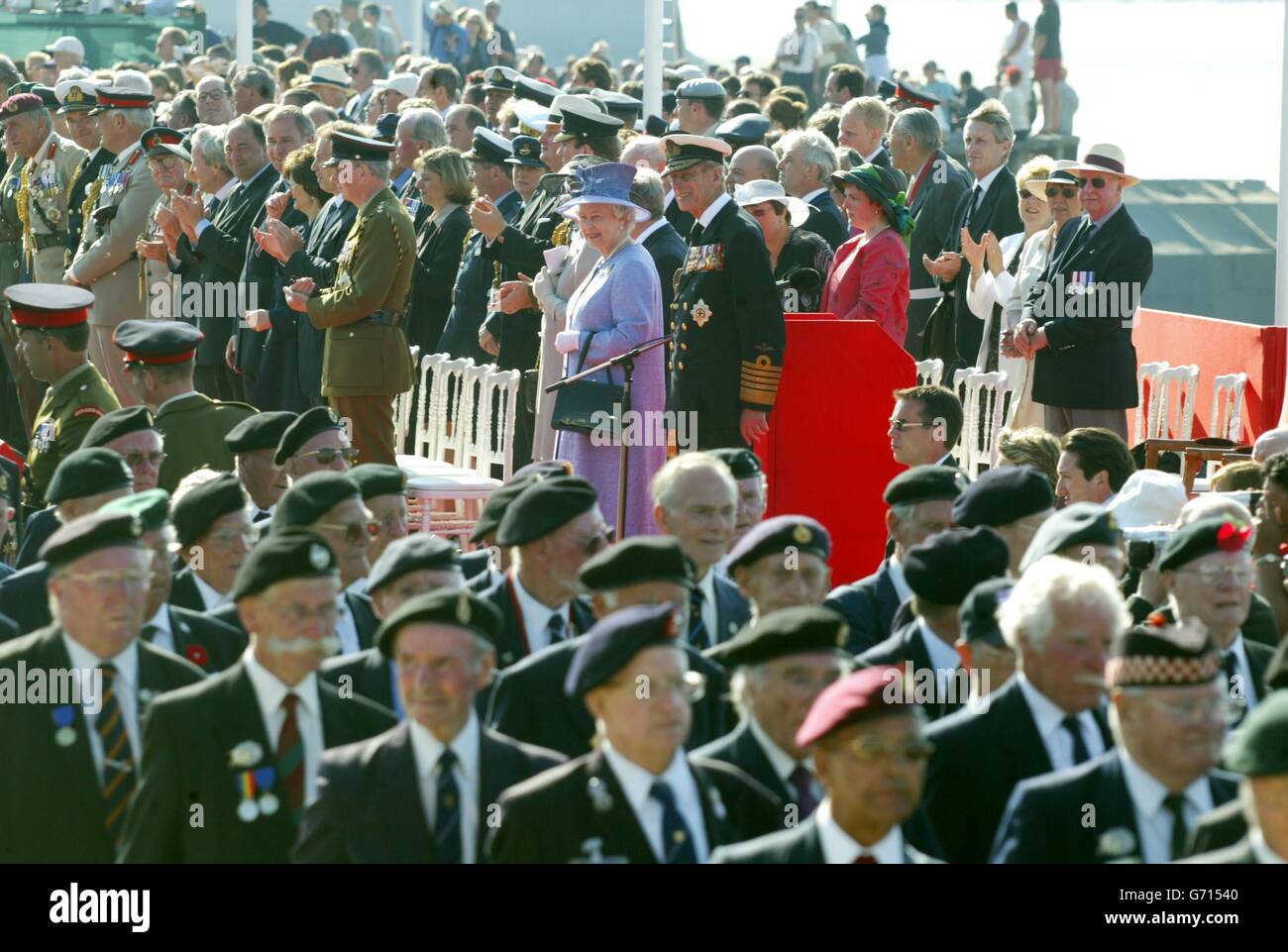 La Regina Elisabetta II della Gran Bretagna guarda i veterani del D-Day che marciano nella piazza di Arromanches, in Francia, come parte del 60° anniversario degli sbarchi in Normandia. Foto Stock