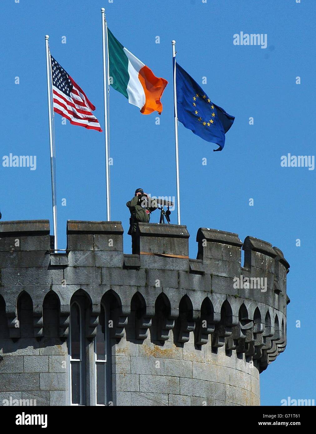 Le bandiere degli Stati Uniti, dell'Irlanda e dell'UE sorvolano il castello di Dromoland, nella contea di Clare, in Irlanda, mentre un ufficiale dell'esercito guarda la campagna circostante. Il presidente DEGLI STATI UNITI George Bush sta partecipando a un importante vertice UE-USA a Dromoland Castle, nel quadro della più grande operazione di sicurezza mai realizzata nello stato irlandese. Foto Stock