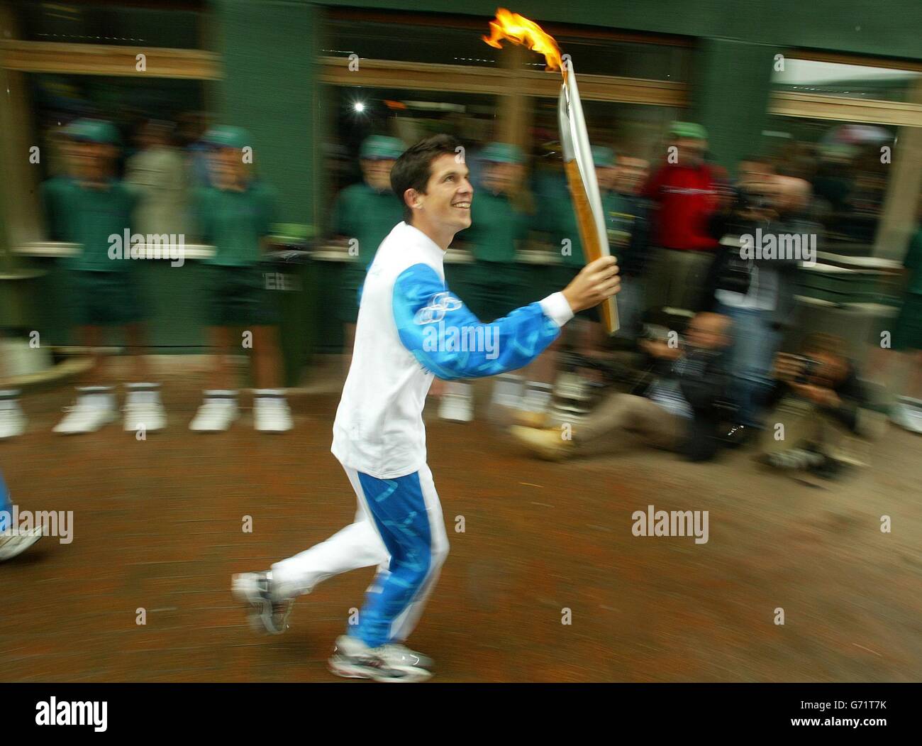 Tim Henman attraversa l'All England Lawn Tennis Club con la torcia olimpica di Wimbledon. In seguito Henman passò la fiamma all'ex campione Virginia Wade per il viaggio nel centro di Londra. Foto Stock