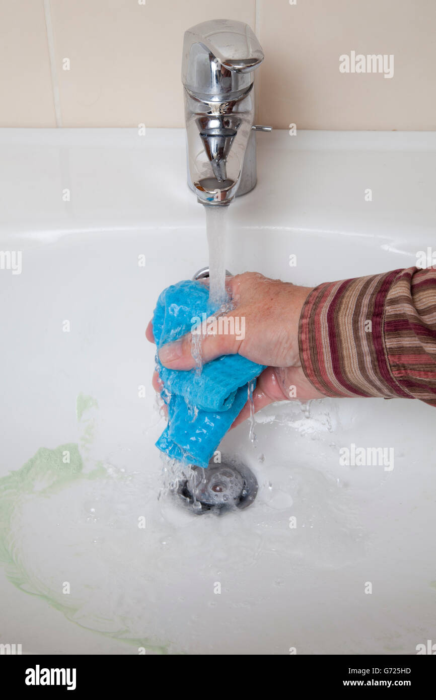 Lavandino che viene pulita, acqua corrente del rubinetto, il lavaggio a mano su un panno spugna Foto Stock
