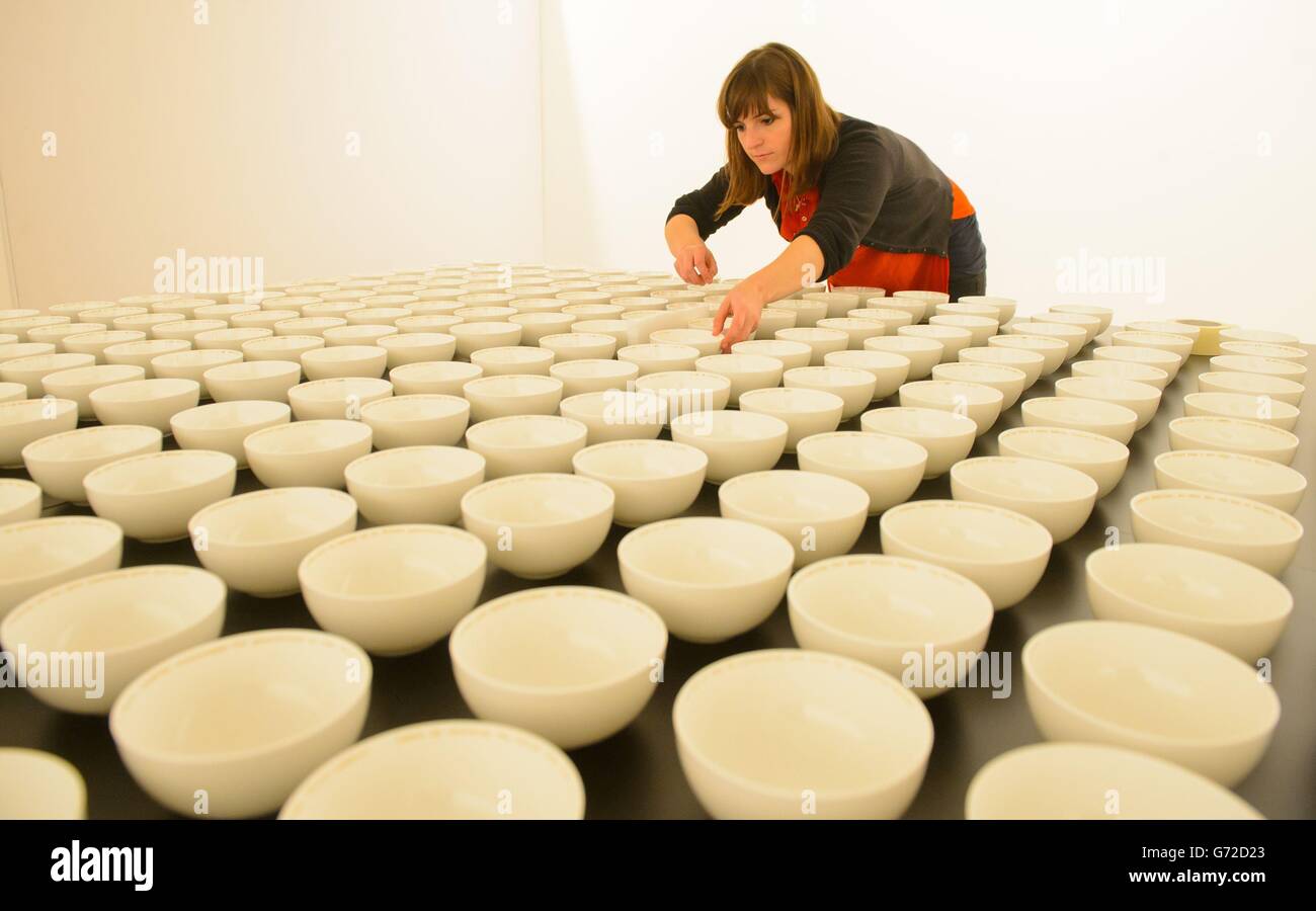 Un volontario aiuta a installare 'Everyman's Dream' di Clare Twomey, una collezione di 1,000 ciotole in ceramica, ciascuna inscritta con una frase che descrive il sogno di una persona per la loro vita all'undicesima fiera internazionale Collect alla Saatchi Gallery di Chelsea, a ovest di Londra. Foto Stock