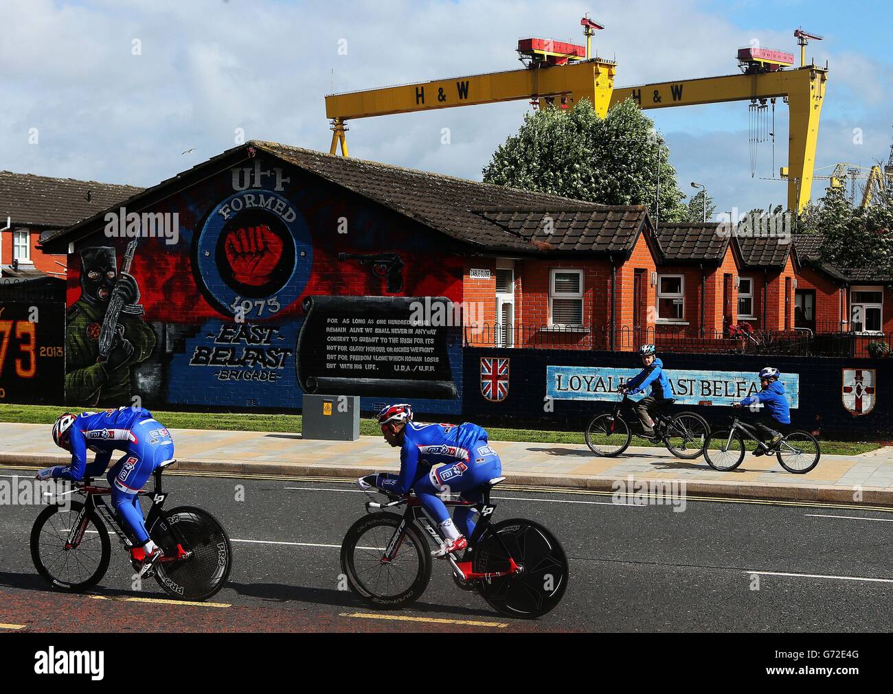 Due giovani ciclisti si guardano mentre i membri del team FDJ.fr si fanno strada sulla Newtownards Road a Belfast durante la sessione di prove cronometrate del Team prima della tappa uno del giro D'Italia 2014. Foto Stock