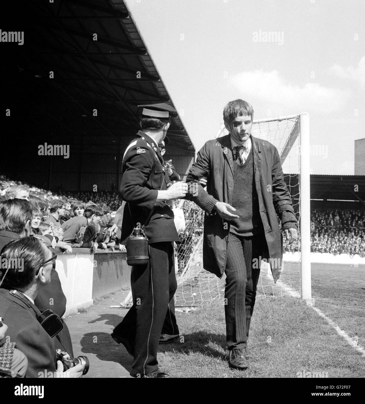 Con il sangue che si deforma sul viso, uno spettatore viene guidato dalla folla da un uomo in ambulanza durante il primo incontro di divisione tra West Ham United e Manchester United a Upton Park. Foto Stock