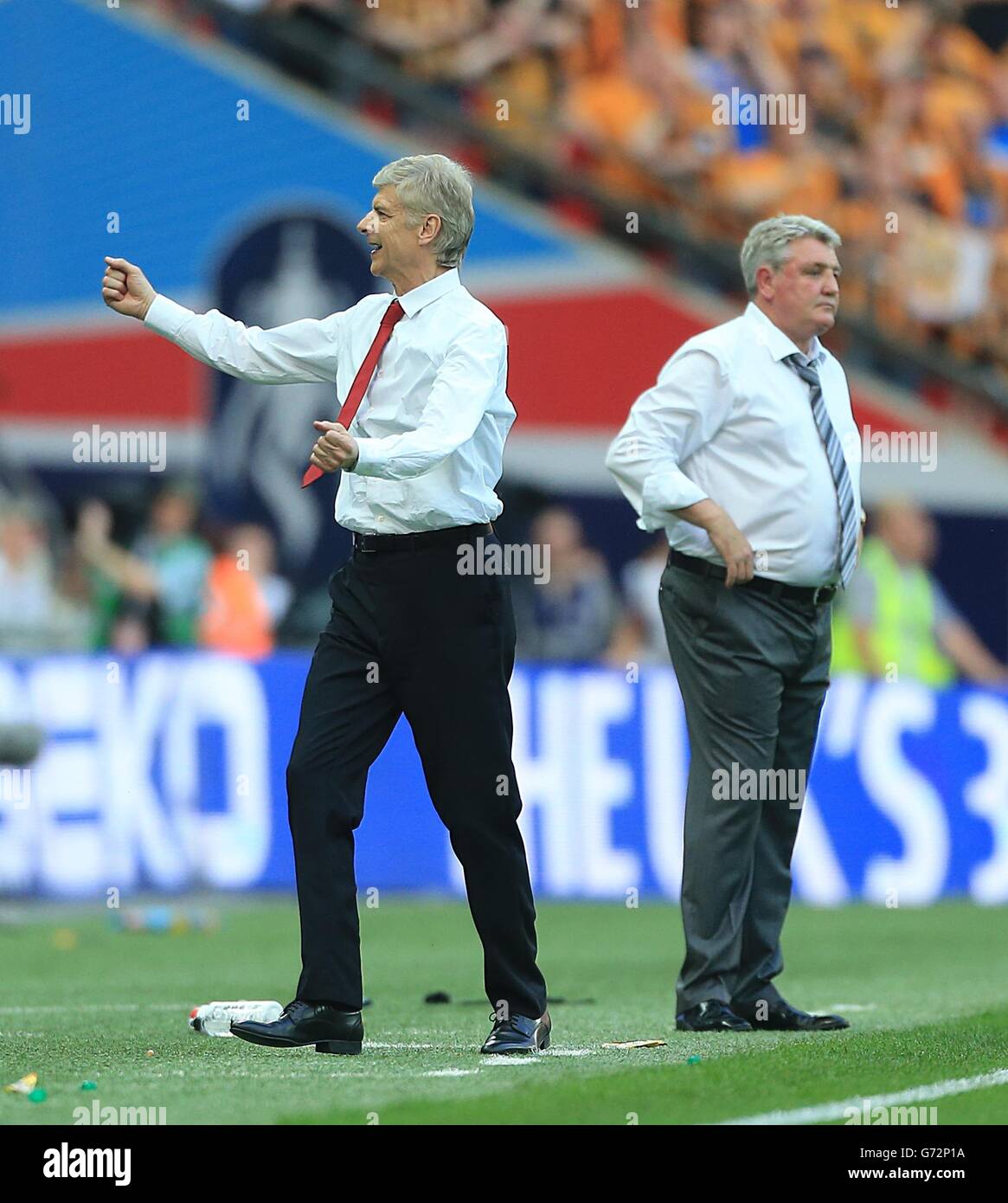 Il manager Arsenal Arsene Wenger (a sinistra) festeggia al fischio finale Come il manager di Hull City Steve Bruce guarda sopra Foto Stock