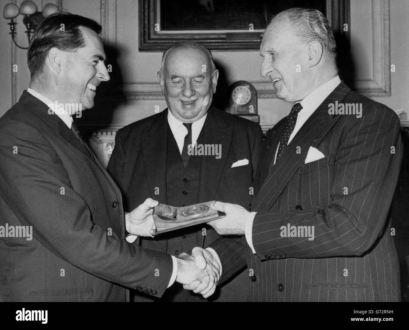 Il campione del mondo di corse automobilistiche Jack Brabham (l) riceve dal Marchess Camden, presidente del Royal Automobile Club Competitions Competitions Committee (r), una medaglia d'oro per il suo unico risultato nella vittoria dei campionati del conducente e del costruttore nello stesso anno. Nel centro si trova Howard Mathias, vicepresidente senior del RAC, che ha presieduto una cena presso la sede centrale del Pall Mall del club al momento della presentazione. Foto Stock