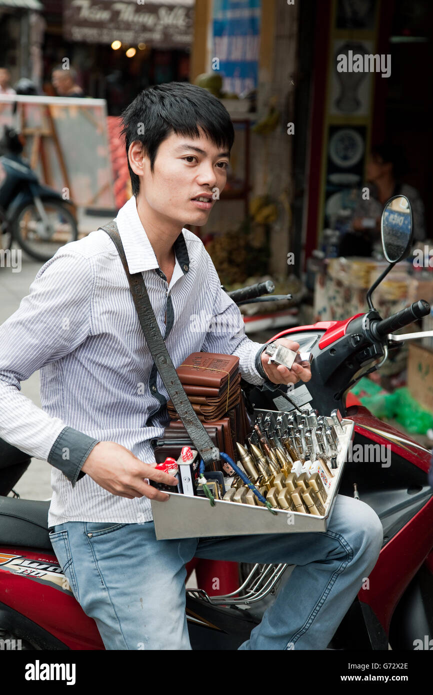 Vietnamese street fornitore offre la guerra negozio di souvenir in vendita ad Hanoi, Vietnam Foto Stock