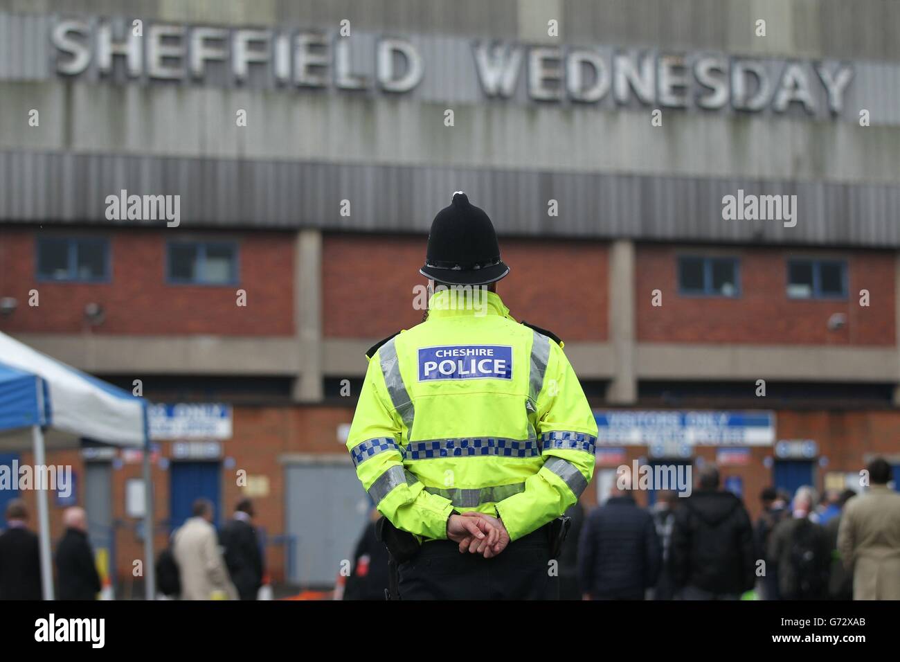 La polizia guarda come i membri dei mezzi di comunicazione ispezionano l'area fuori dall'area di Lepping Lane dello Stadio Hillsborough, Sheffield, durante una visita a da parte dei giurati per l'inricerca nella morte di 96 tifosi di calcio di Liverpool uccisi nel disastro di Hillsborough. Foto Stock