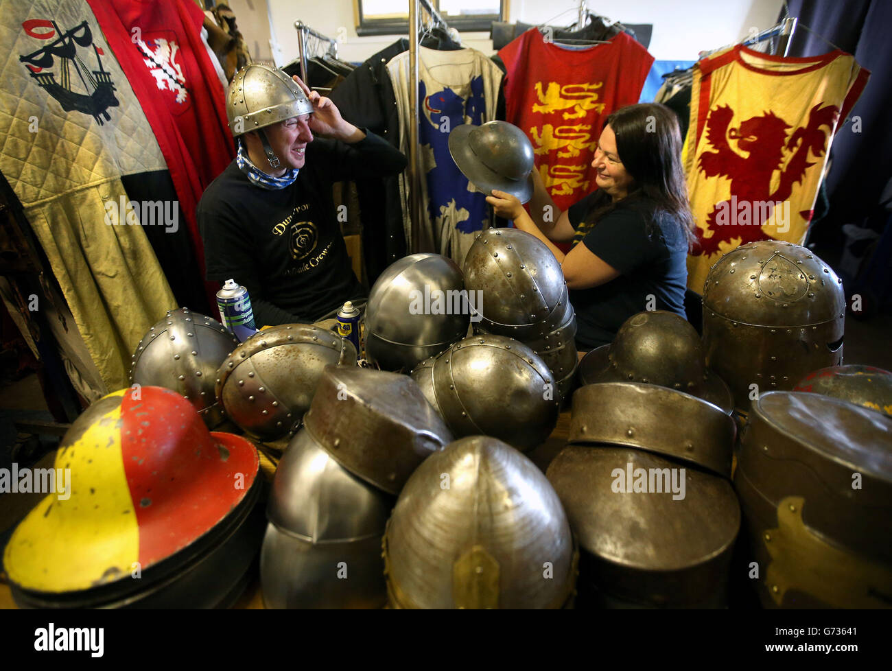 Annette Grier con Keith Bremner della Clranald Trust mentre cerca di indossare un casco mentre si allinea, Lucida e fissa le cinghie ai caschi, oltre a regolare i costumi durante i preparativi finali per la Battaglia di Bannockburn che si terrà a Bannockburn Live Event a Bannockburn il 28 e 29 giugno, come la Battaglia di Bannockburn del 700 ° anniversario è celebrato. Foto Stock